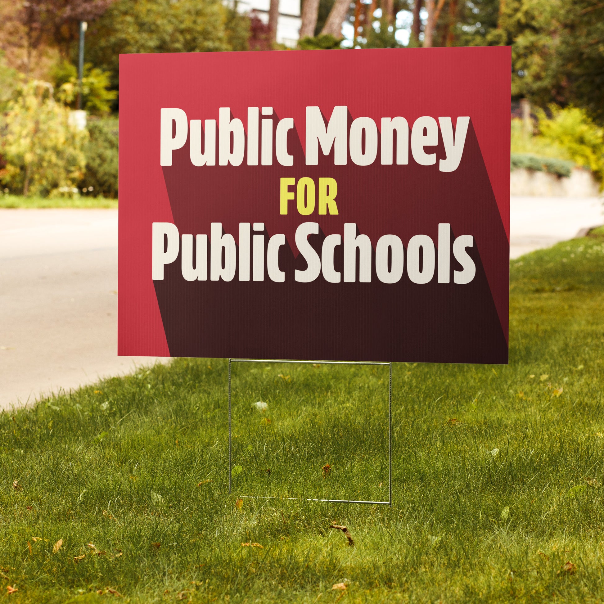 Red sign on grass with 'Public Money for Public Schools' text