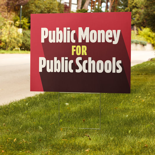 Red sign on grass with 'Public Money for Public Schools' text